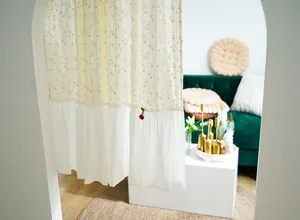 Detailed view of floral daisy door curtain with white ruffle trim in a bright cozy room.