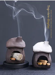 Detailed view of miniature ceramic fireplace sage holder with burning palo santo wood smoke