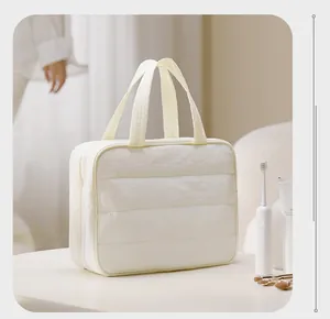 Quilted white toiletry bag on bathroom counter with toothbrush and skincare props