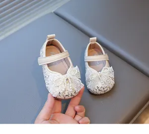 Primer plano de zapatos de princesa para bebé con lazo de encaje, perlas y lentejuelas.
