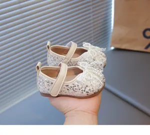 Detalle de zapatos de gateo para bebé con lentejuelas crema y lazo de encaje con perlas