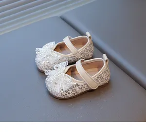 Primer plano de zapatos de princesa para bebé con lentejuelas plateadas y lazo de perlas