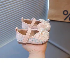 Vista detallada de zapatos de princesa rosa con lentejuelas y lazo de perlas para bebé.