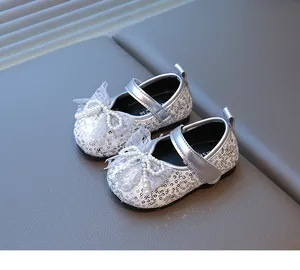 Vista detallada de zapatos de bebé con lentejuelas plateadas, lazo de encaje y perlas