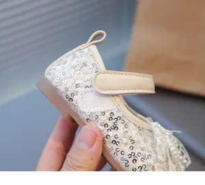 Detalle de zapato de bebé con lentejuelas y lazo de encaje con perlas