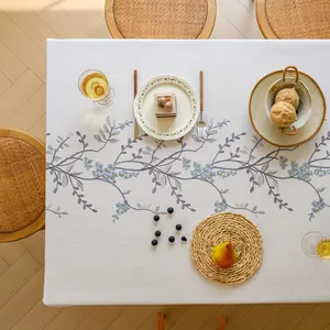 Top-down view of an embroidered floral tablecloth with elegant table setting details