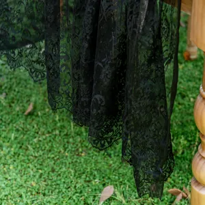Close-up detail view of elegant black floral lace tablecloth with delicate scalloped edges