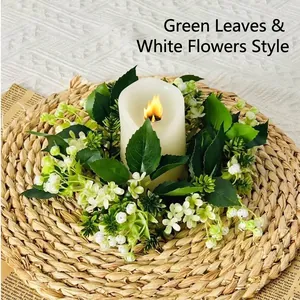 Primer plano de un aro para vela con hojas verdes y flores blancas sobre un mantel