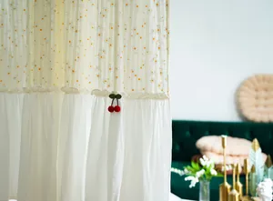 Detail of cotton fabric curtain with daisy patterns and a cute red cherry ornament