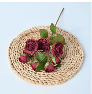 Macro view of artificial deep red roses with burnt-edge petals on woven straw mat