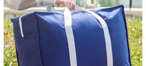 Durable blue moving storage bag with strong white handles for quilts.