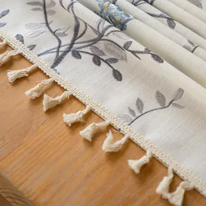 Macro view of elegant linen tablecloth with delicate leaf embroidery and tassels