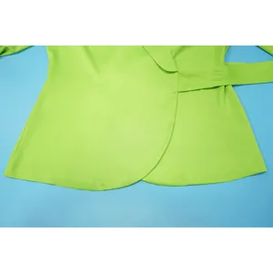 Detailed macro view of vibrant lime green wrap top with curved hem and matching fabric waist belt