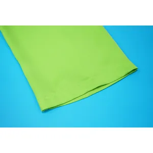Macro detail view of lime green garment fabric highlighting fine stitching and high-quality hem