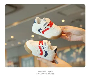 Nahaufnahme weißer Kleinkind-Sneaker mit rot-blauen Streifen und Klettverschluss