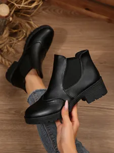 Detailansicht der schwarzen Chelsea-Boots mit Blockabsatz und feinem Brogue-Muster sowie Gummizug