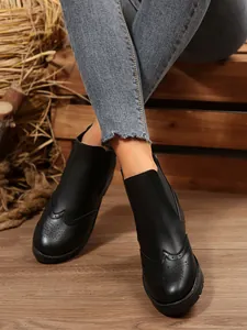Nahaufnahme schwarzer Wingtip-Martin-Stiefel an Model mit Jeans in rustikaler Umgebung