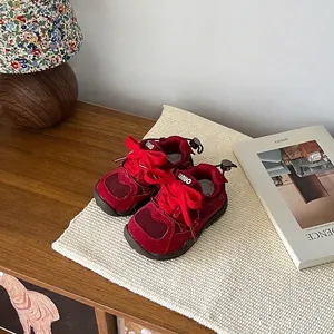 Detail of red mesh children's sneakers on a woven mat in a cozy indoor setting.