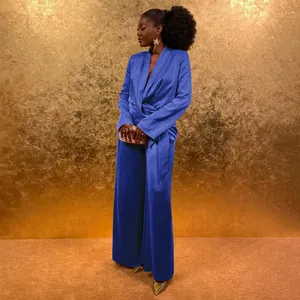 Elegant blue satin blazer and wide-leg trousers set on model against gold background