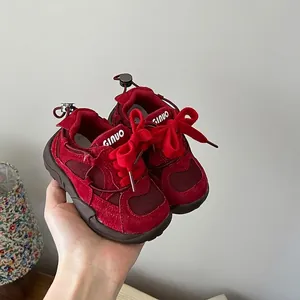 Macro detail view of red mesh children's sneakers featuring stylish bow tie laces