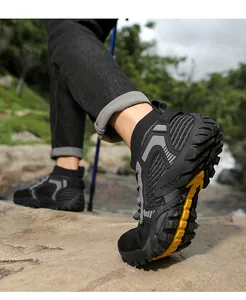 Close-up of breathable black hiking shoes with yellow grip outsole on a rock