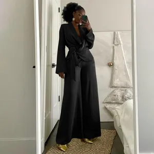 Detailed view of women's black satin wrap top and wide-leg trousers set in mirror selfie