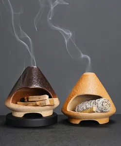 Close-up of ceramic incense burners shaped like mini fireplaces burning Palo Santo and sage.