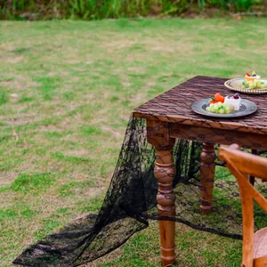 Vue détaillée de la nappe en dentelle noire aux motifs floraux sur table en bois