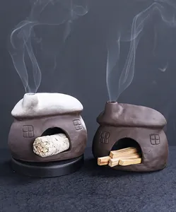 Κοντινό πλάνο δύο κεραμικών θυμιατηριών σε σχήμα σπιτιού με καπνό και φασκόμηλο
