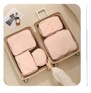 Set aus rosa Nylon-Packwürfeln, organisiert in einem Koffer mit Reisezubehör