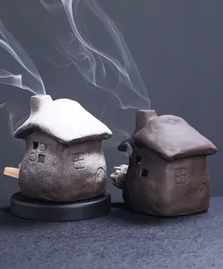 Detailed close-up of ceramic cottage incense burners with smoke rising from tiny chimneys