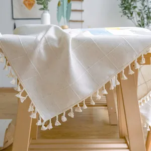 Detailansicht einer cremefarbenen Tischdecke mit Karomuster und Zierquasten am Rand