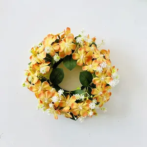 Primo piano di una ghirlanda di candele con fiori selvatici artificiali arancio e bianchi