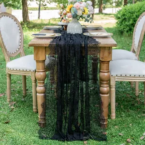 Elegant black lace table runner detail on a rustic wooden table in a garden setting