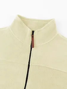 Detail of cream polar fleece sweatshirt with high collar and leather zipper pull tab.