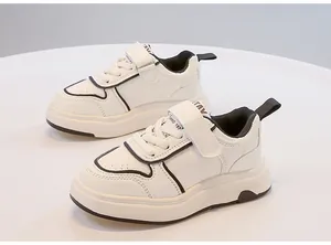 Primo piano di scarpe da ginnastica bianche per bambini con profili neri e velcro