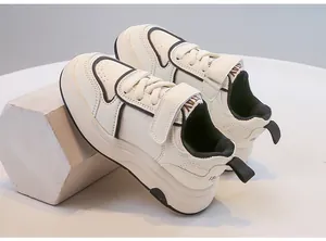 Vista laterale di scarpe sportive bianche per bambini con chiusure a velcro e bordi neri