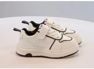 Dettaglio di scarpe da ginnastica bianche per bambini con profili neri e velcro.