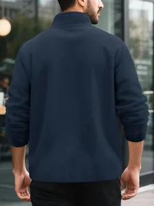 Back detail view of a navy blue polar fleece warm sweatshirt on a male model standing outdoors
