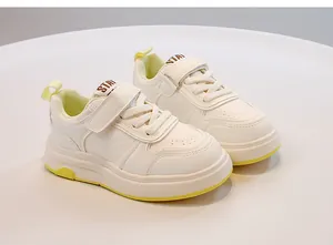 Primo piano di scarpe sportive bianche per bambini con accenti gialli e velcro