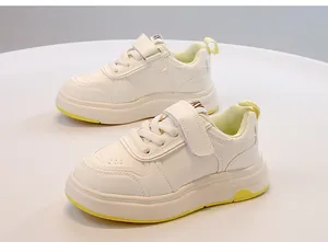 Vista dettagliata di sneaker bianche per bambini con accenti gialli e chiusura a strappo.