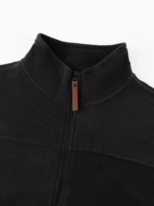 Close-up of men's black fleece sweatshirt collar with half-zip and leather pull tab