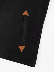 Detail view of a black fleece jacket featuring a vertical zipper and brown leather accents.