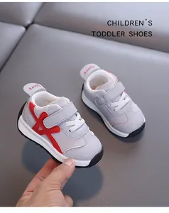 Nahaufnahme grauer Kleinkinderschuhe mit rotem Kreuzdesign und Klettverschluss