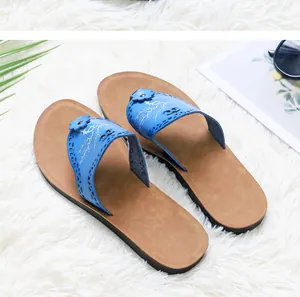 Close-up of blue floral PU leather slippers with decorative flower on white fur rug