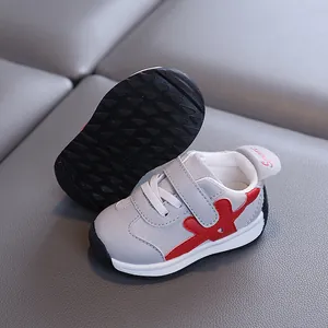 Atmungsaktive graue Wildleder-Sneaker für Kleinkinder mit roten Akzenten und rutschfester Sohle.