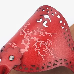 Close-up of red PU leather slippers with laser-cut patterns and floral print
