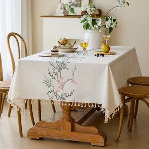 Close-up of embroidered floral patterns and tassel edges on an ivory linen tablecloth