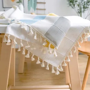 Detailansicht einer karierten Tischdecke mit dekorativen Quasten und reicher Stoffstruktur