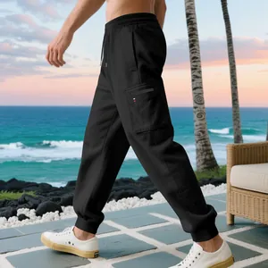 Detailed side view of men's black heavy cargo joggers with pockets in beach setting